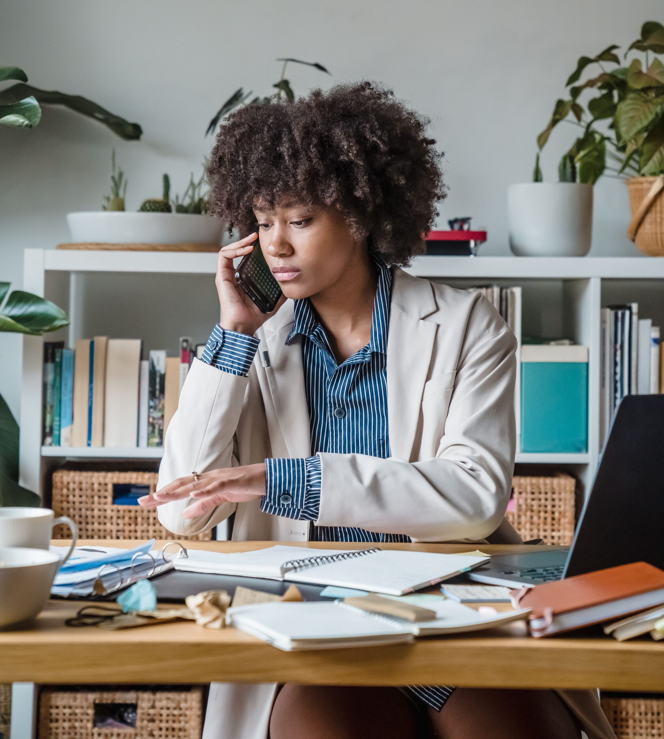 Busy professional juggling a phone call and multiple tasks at her desk.